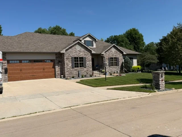 Gray architectural asphalt shingle roof on stone and brick residential home with gable design
