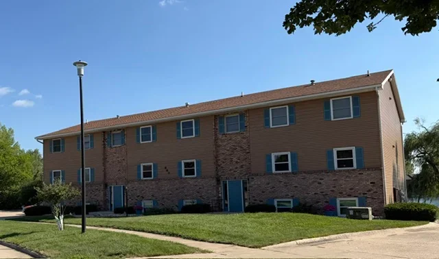 Two-story brick and vinyl residential building with newly installed asphalt shingle roof