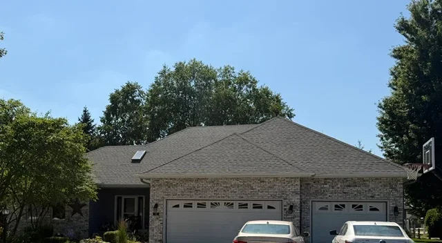 Charcoal gray architectural shingle roof on brick residential garage with two doors
