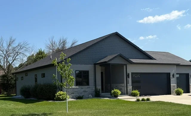 Dark asphalt shingle roof on modern residential home with gabled design and garage