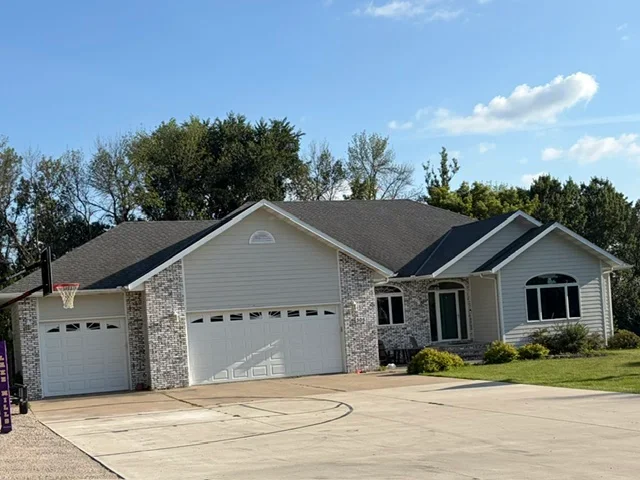 Dark architectural shingles installed on residential home with multiple roof pitches and brick accents